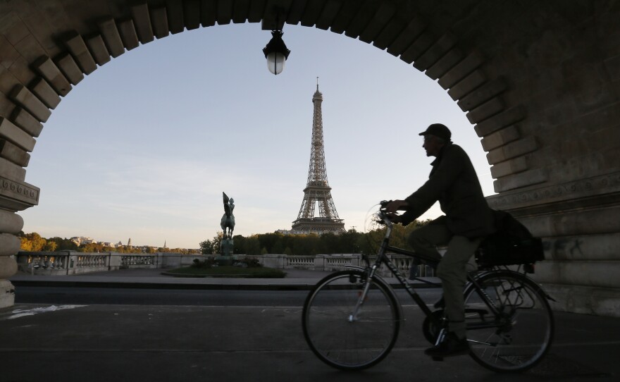 A man takes an early morning bicycle ride across a bridge near the Eiffel Tower in Paris.