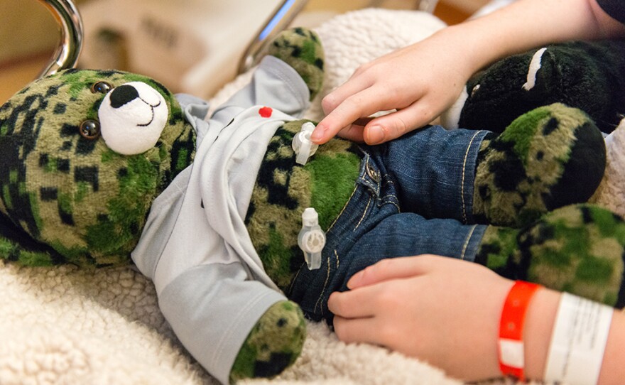 Matthew Husby points to a gastrostomy tube on his teddy bear that is similar to the one surgeons inserted in his own stomach. Role-playing helps kids relax, doctors say.