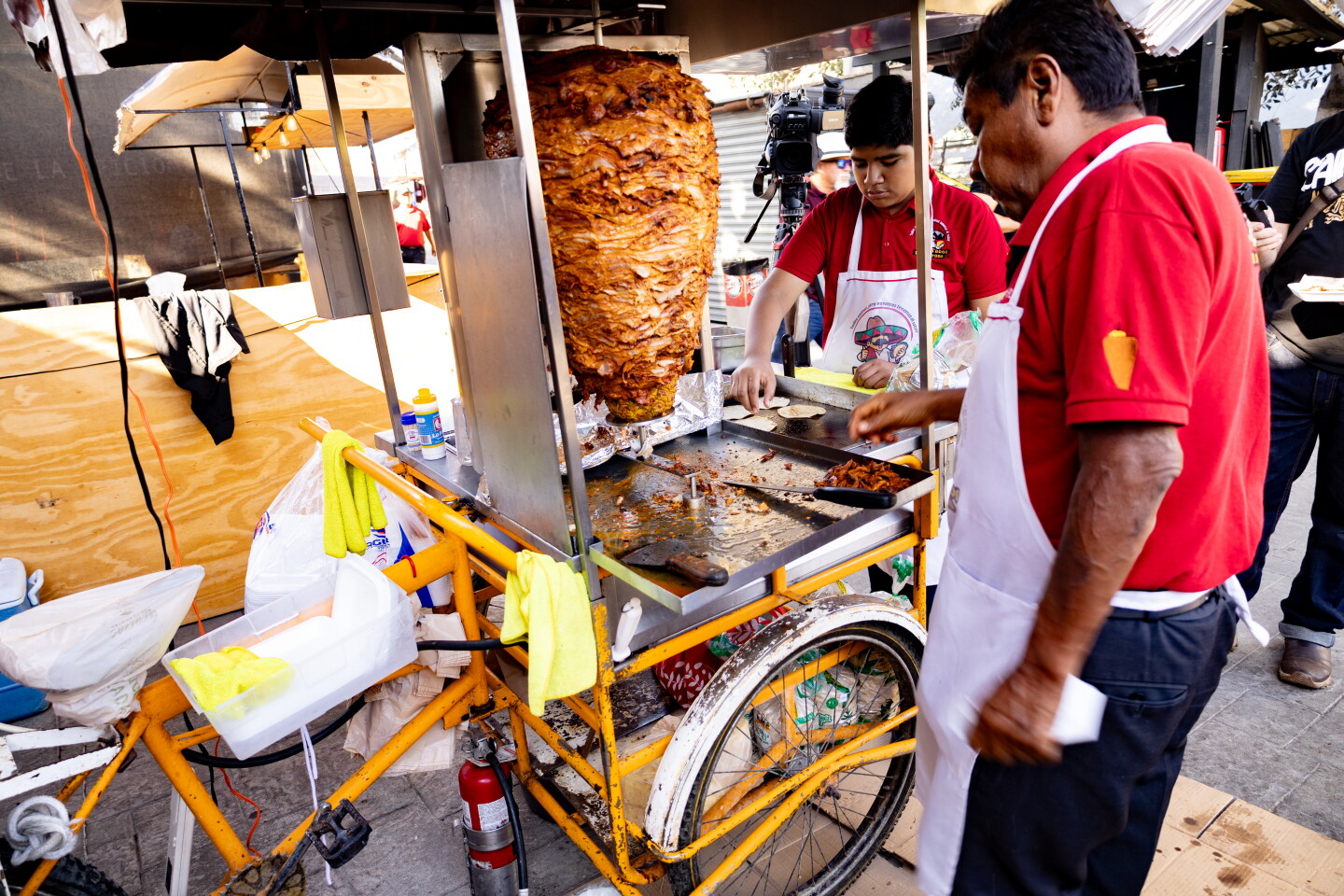 A man and his grandson carve meat for tacos at the Taco El Sabroso taco stand on July 31, 2026.