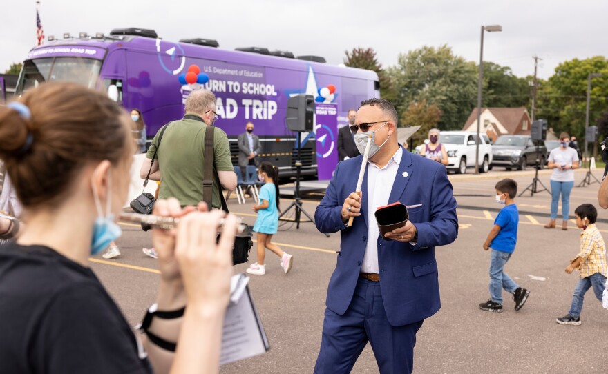 U.S. Education Secretary Miguel Cardona accompanies North High School's marching band on the cowbell during a Monday pep rally in Eau Claire, Wis.