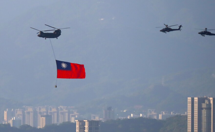 A military helicopter carrying a Taiwan flag flies over near the Taipei 101 building, as part of the rehearsal ahead of the Double Ten National Day celebration, amid China's growing military threats, in New Taipei, Taiwan, on Tuesday.