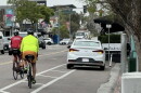 Two cyclists ride past a car parked in the bike lane of 30th Street in North Park.
