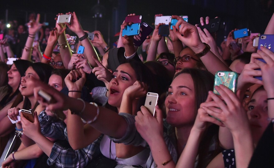 Concertgoers use their cellphones during a Fifth Harmony concert March 23, 2015, in New York. The company Yondr created a locking pouch to hold phones during performances, creating a "phone-free zone."
