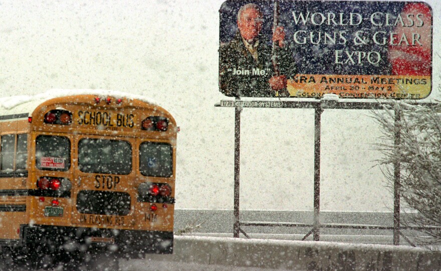 A school bus in 1999 passes a billboard advertising the NRA's annual meeting in Denver, previously scheduled to take place just 10 days after the shooting at Columbine High School.