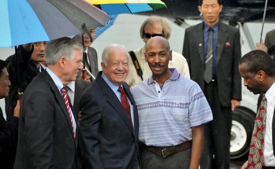 In this photo released by China's Xinhua news agency, former U.S. President Jimmy Carter, center left, poses with American Aijalon Gomes, center right, at Pyongyang airport, North Korea, on Friday Aug. 27, 2010.