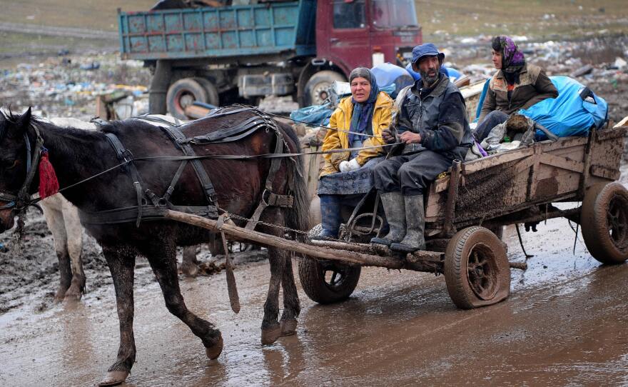 A Roma family rides a horse-drawn cart carrying scrap metal out of Romania's Pata-Rât city dump.