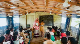 Hosne Ara teaches a group of fourth graders, seated on benches inside the floating school's classroom.