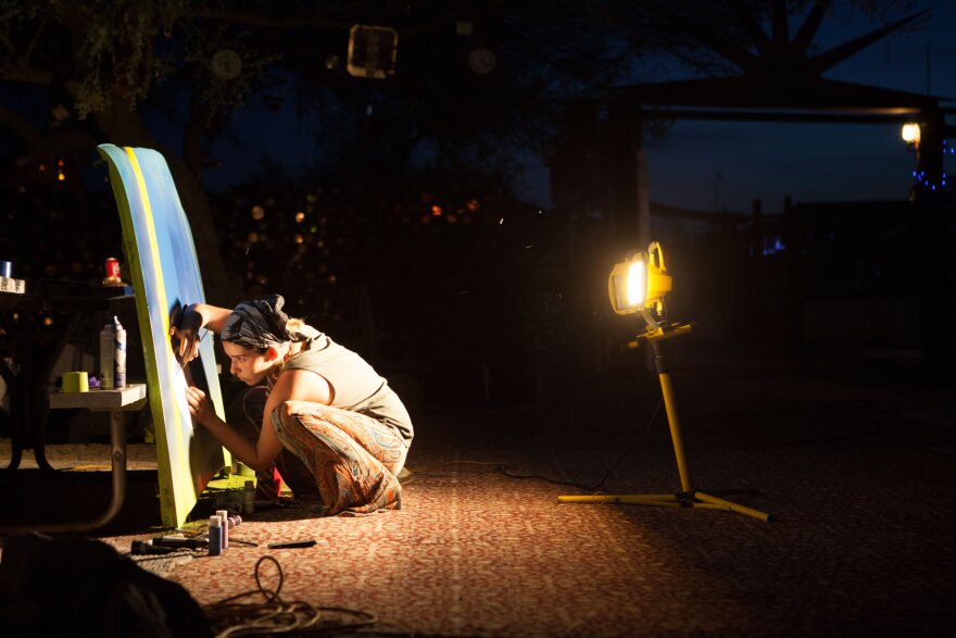 An artist works on a painting at night in East Jesus, March 28, 2015. 