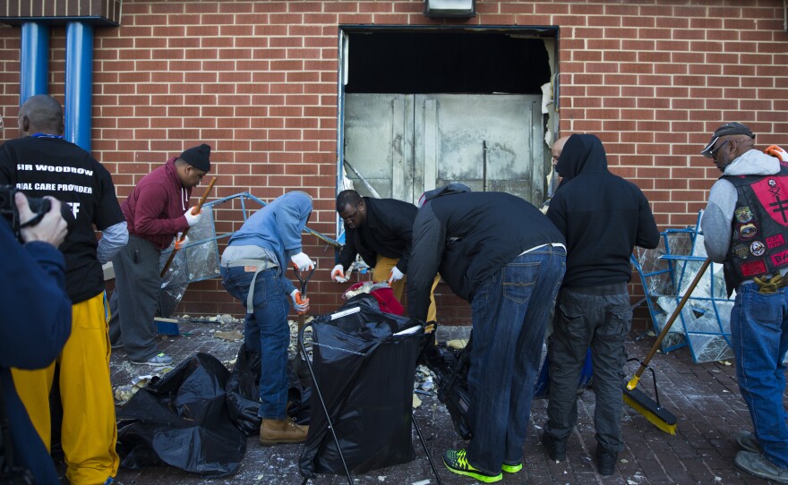 Maryland state troopers stand by Tuesday as people clean up outside a CVS pharmacy in Baltimore.