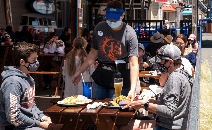 Patrons wear masks as they sit on the outdoor patio of a restaurant on Pier 39 at Fisherman's Wharf in San Francisco. California is among more than 20 states that require face masks to help combat the spread of the coronavirus.