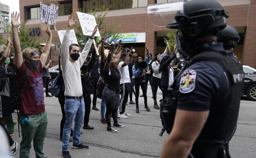 Protesters chant near police, Wednesday, Sept. 23, 2020, in Louisville, Ky. A grand jury has indicted one officer on criminal charges six months after Breonna Taylor was fatally shot by police in Kentucky.