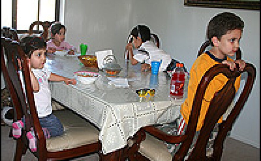 Rawa Bahou's three children sit with their cousin (right) for dinner. Bahou and her children live share a two-bedroom apartment in suburban Detroit with her brother-in-law, his wife and their two children.