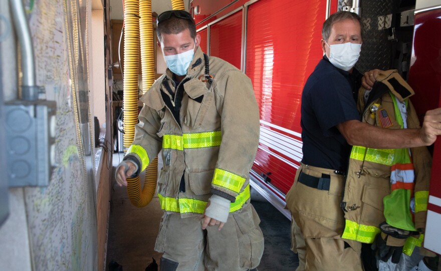 Fire Capt. Rick Rees, right, makes room for paramedic Jake Swan to get into a truck at Fire Station 4 in Fallbrook, Aug. 6, 2020. Firefighters say the narrow space in the station is one of several factors that can slow their response.