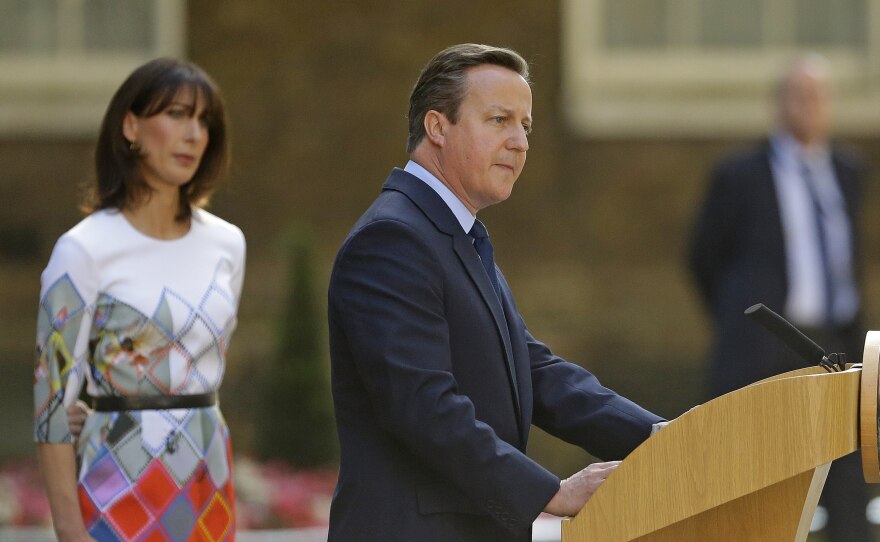 Britain's Prime Minister David Cameron speaks outside 10 Downing St., London, as his wife, Samantha, looks on. Cameron says he will resign by the time of the Conservative Party conference in the fall.