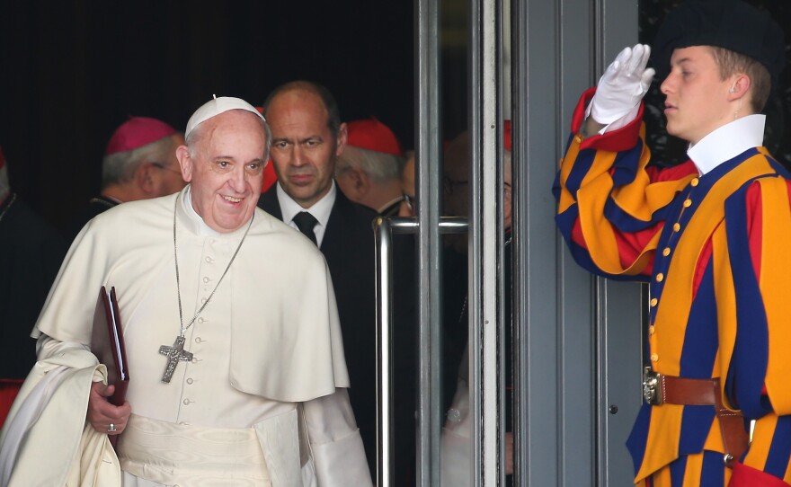 Compared with a Swiss Guard's get-up, the everyday wear of Pope Francis — shown here in the Vatican in 2014 — is downright plain.