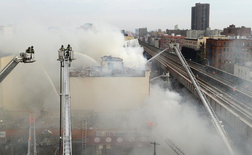 Firefighters try to put out a fire after a reported explosion and building collapse in the Harlem neighborhood of New York City on Wednesday. The cause of the explosion, as well as reports of any injuries, had not yet been determined.