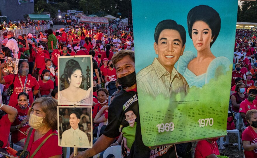A supporter holds pictures of the late dictator Ferdinand Marcos and his wife Imelda Marcos, as Ferdinand "Bongbong" Marcos Jr. and Davao city Mayor Sara Duterte, daughter of President Rodrigo Duterte, take part in a rally to campaign for the presidency and the vice presidency in February, in Manila.