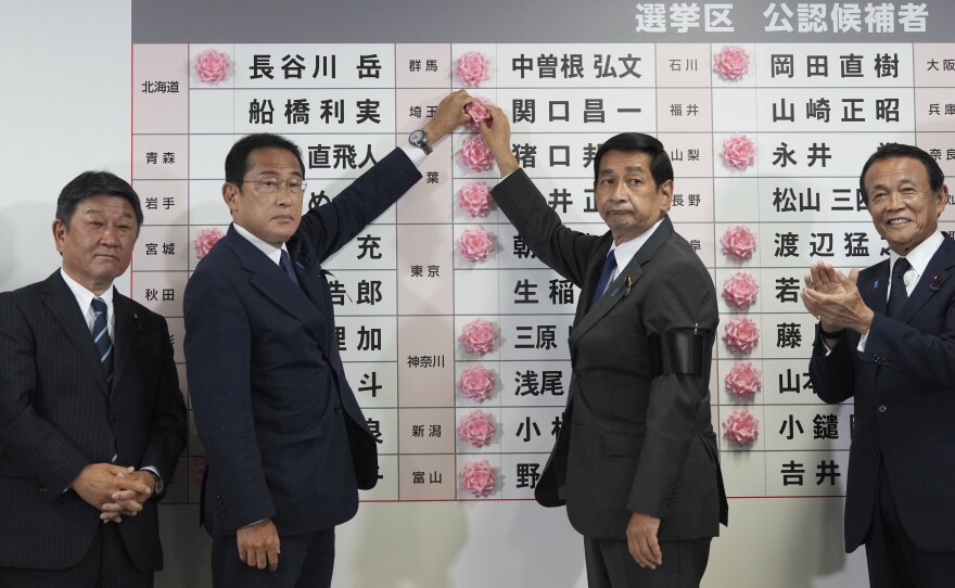 Fumio Kishida, second left, Japan's prime minister and president of the Liberal Democratic Party (LDP), speaks after placing a red paper rose on an LDP candidate's name to indicate a victory in the upper house election.