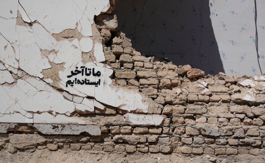 A residential building damaged by recent U.S.-Israeli strikes is seen with a sign on its wall that reads in Farsi: "We stand till the end," in Fardis, west of Tehran, Iran, Friday, April 3, 2026.