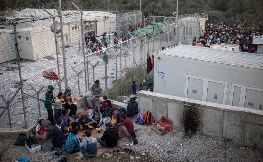 Asylum-seekers gather outside a camp on the island of Lesbos where they're supposed to be screened quickly. But sometimes the wait can last days.