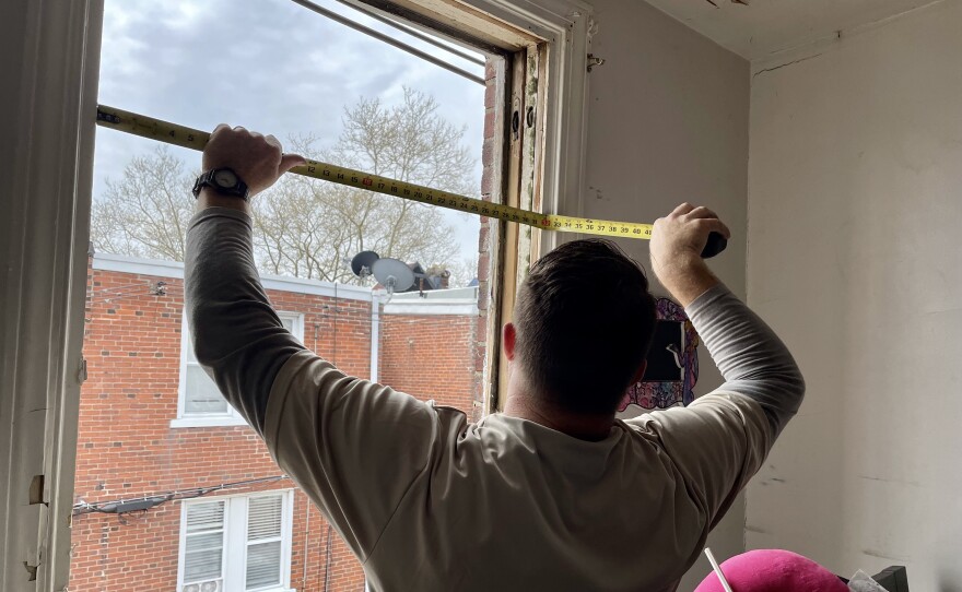 A carpenter from PC Weatherizing prepares to install a new, double-glazed window in Rezephyr Young's house, as a part of a holistic home repair program called Built to Last.