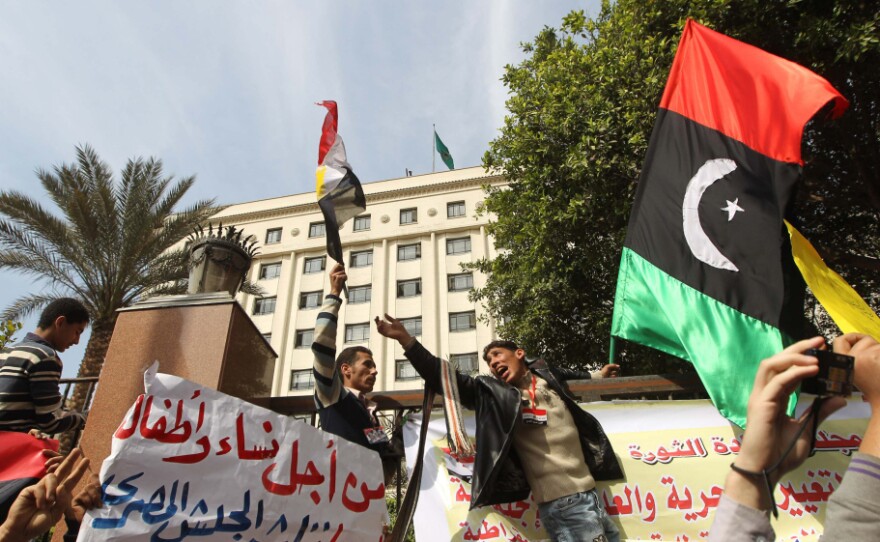 Protesters shout slogans against Libyan leader Moammar Gadhafi as they hold up the old Libya flag during a demonstration Tuesday outside the Arab League headquarters in Cairo.