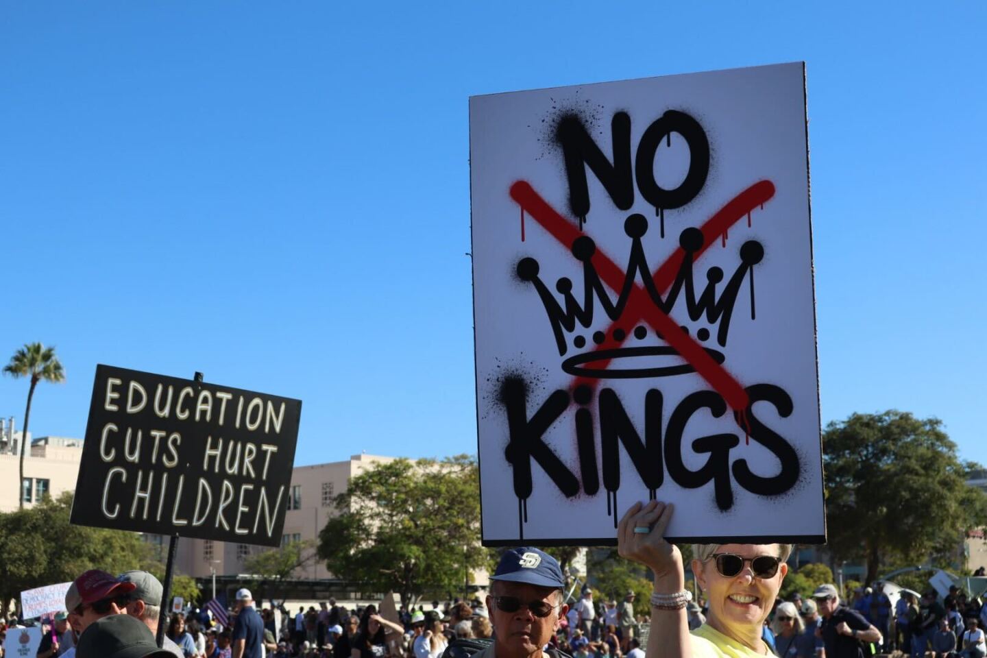Protesters hold up signs during a demonstration for a 'No Kings' rally in San Diego on Oct. 18, 2025.
