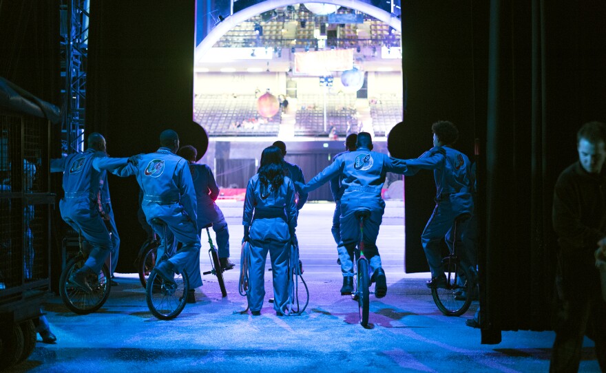 A team of unicyclists hold on to each other backstage. The King Charles Troupe has been playing basketball on unicycles since the '60s.