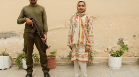 Khadija Saddiqi, 22, stands outside her family home with an armed guard who was assigned to protect her by the wife of the chief minister of Punjab. Saddiqi won a case against a classmate who tried to stab her to death in May last year after she ignored his advances.