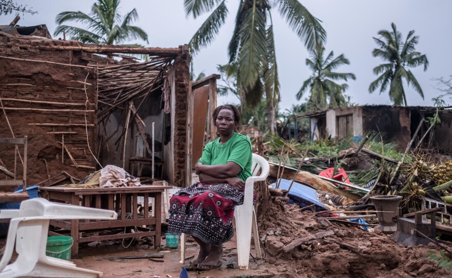 Tamazina Carlos sits outside what remains of her house. The school assistant escaped just before the ceiling caved in. Since the cyclone hit on Thursday, she has been sleeping under a pile of palm fronds.
