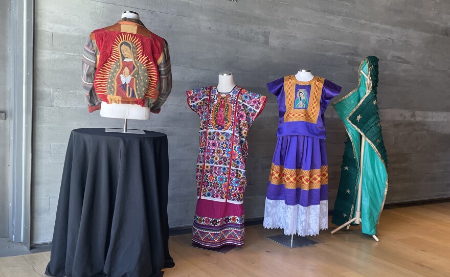 Works from the Mingei's "Fashioning an Icon" exhibit are shown on March 24, 2025. Local artist and fashion designer Claudia Rodríguez-Biezunski's jacket is shown at left. Local artist Diana Benavídez's green, piñata-style cape is shown on the far right.