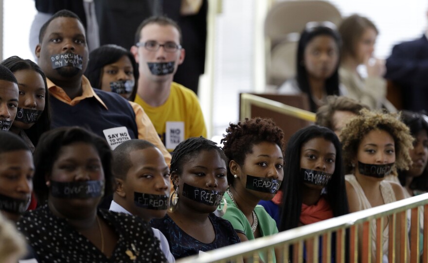 Opponents of North Carolina's new voter ID legislation wear tape over their mouths while sitting in the gallery of the House chamber of the North Carolina General Assembly in Raleigh, N.C., on April 24, where lawmakers debated new voter laws. On Monday, Gov. Pat McCrory signed a new law that will require a state-approved photo ID to vote and cut early-voting opportunities.