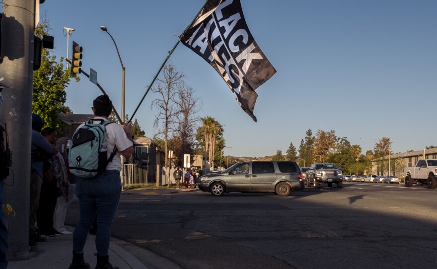 A protester waves a Black Lives Matter flag on the corner of Ashwood and Mapleview in Lakeside Saturday, early evening, during a rally and protest against hate in response to the stabbing of a teenage black girl by a 16-year-old boy, an apparent hate crime, April 23, 2022.