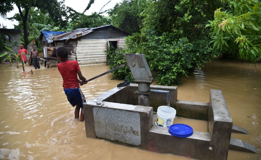 A boy pumps water close to his family's flooded home in Leogane on Wednesday.