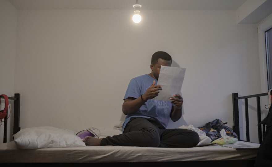 Tony reads a paper on a bed at the home.