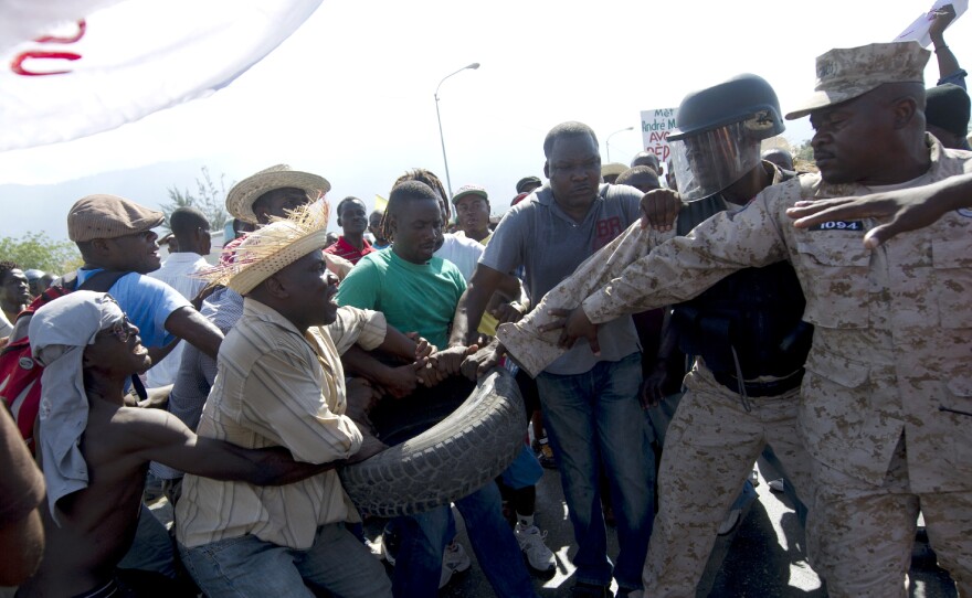 Haitian police try take a tire from protesters during a march against the government of Haitian President Michel Martelly in Port-au-Prince, on Jan. 8. Protesters marched through the streets calling for the resignation of the Haitian leader.