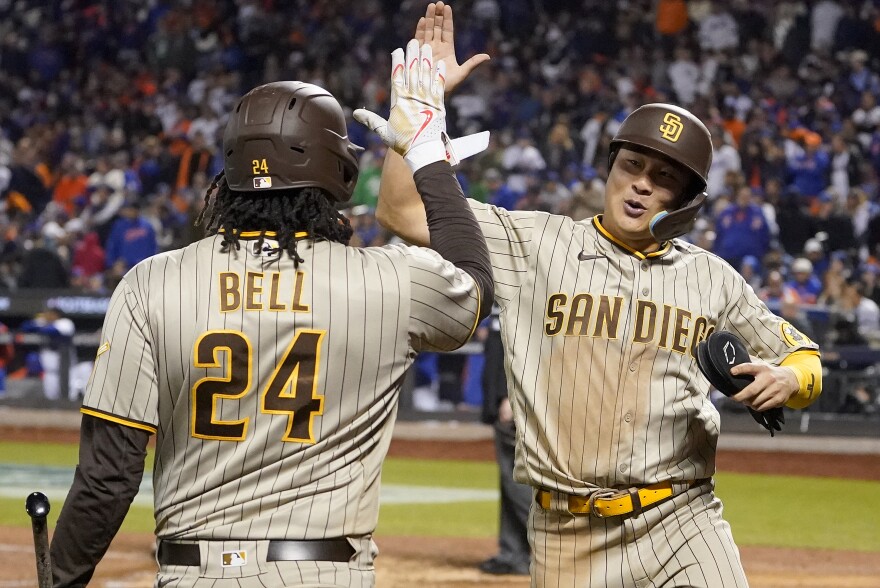 San Diego Padres shortstop Ha-Seong Kim, right, celebrates with first baseman Josh Bell (24) after scoring on a hit by Juan Soto against the New York Mets during the eighth inning of Game 3 of a National League wild-card baseball playoff series, Sunday, Oct. 9, 2022, in New York.
