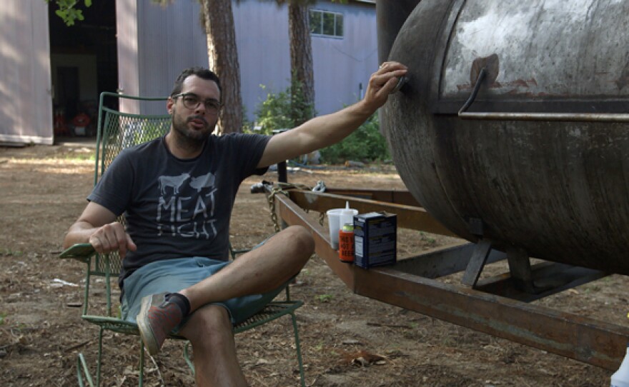 Aaron Franklin, owner and chief firestarter at Franklin BBQ in Austin, is widely regarded as one of the most influential pitmasters in the United States. He is sitting next to his smoker in this photo.