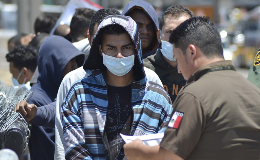 U.S. Border Patrol officers return a group of asylum-seeking migrants to Mexico as Mexican officials check the list, in Nuevo Laredo.