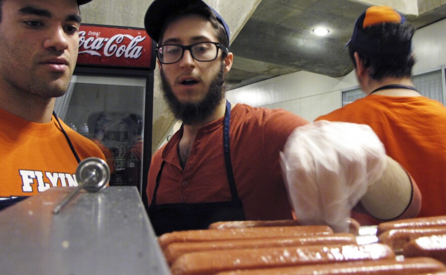 University of Illinois student Stanley Dayan, left, and Chabad Jewish Center employees Mordy Kurtz, center, and Yosef Peysin work at the center's kosher food stand in 2013 at the university's State Farm Center basketball arena in Champaign, Ill.