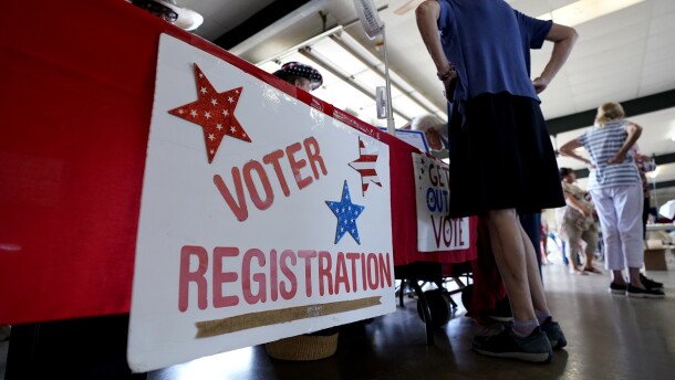 People stand near a voter registration table at a 2022 event in Fredericksburg, Texas.