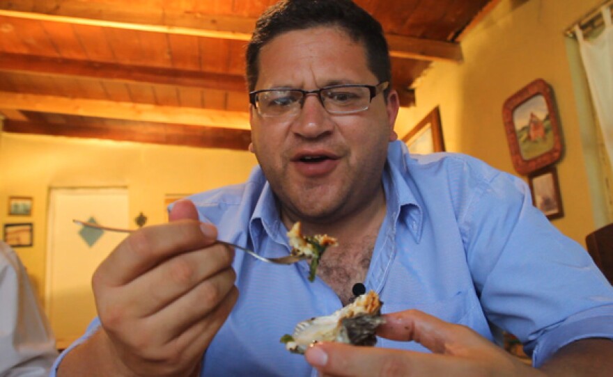 CROSSING SOUTH host Jorge Meraz samples oysters covered with cheese at the La Cava de Marcelo Restaurant.