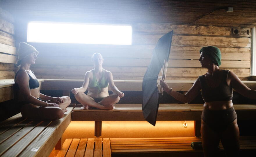 Sauna master Hilde Karlsen (right) is performing a sauna ritual with fan, singing and spreading sauna fragrances, for Kate Rath (center) and Irina Wade at Sukkerbiten in Oslo, Norway, Sept. 25, 2026.