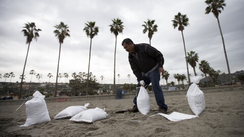 A man fills bags with sand from La Jolla Shores as the San Diego area braces for an approaching storm, Dec. 2, 2014.