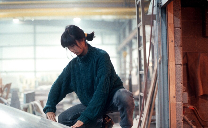 Maya Lin examining inverted water table being fabricated for the Civil Rights Memorial she designed to be installed in Montgomery, Alabama. She is pictured here at the granite fabricator in Barre, Vermont in 1988.