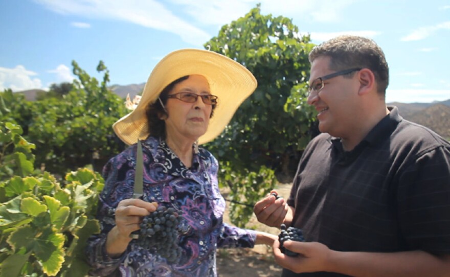 Doña Lupe shows host Jorge Meraz her vineyard and selection of delicious jams.