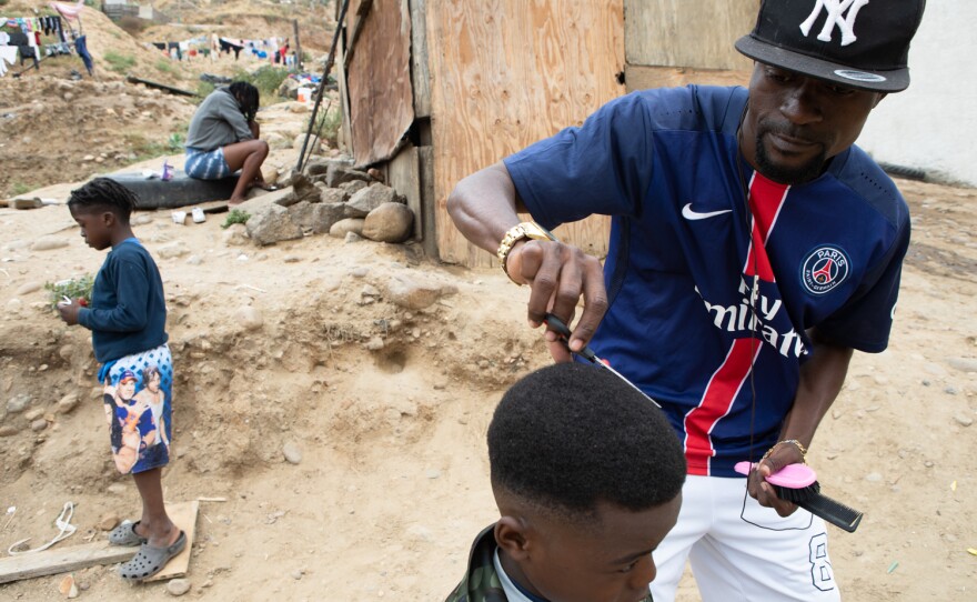 Reegens Novalus cuts the hair of his son, Reedjy, at the Templo Embajadores de Jesús shelter in Tijuana, May 23, 2022. 