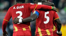 Ghana's John Mensah, center, is consoled by Ghana's Asamoah Gyan, left, after missing a penalty kick.