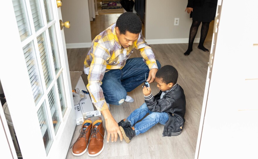 Latroun Epps helps his son, Israel Epps, put on his shoes before they play in their backyard at their Griffin, Ga., home.