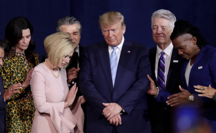 In this file photo from 2020, Pastor Paula White, left, and other faith leaders pray with President Donald Trump, center, during a rally for evangelical supporters at the King Jesus International Ministry church in Miami.